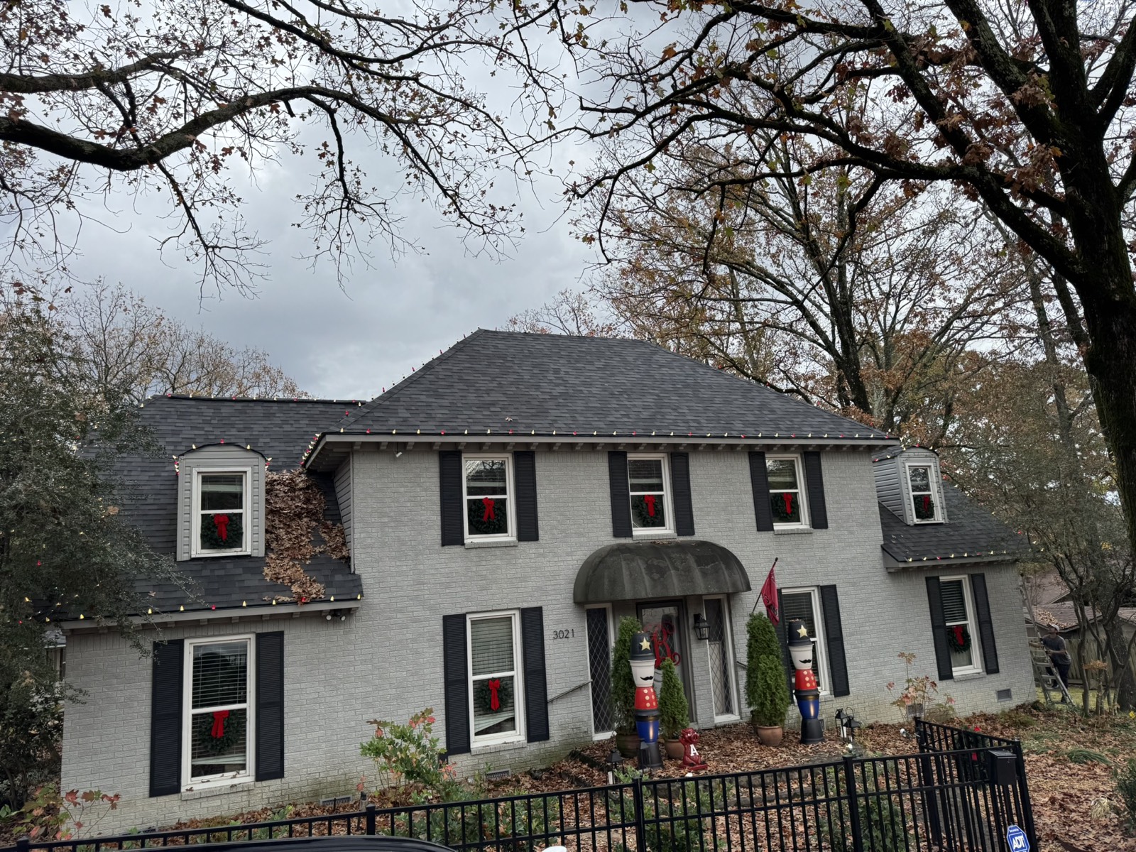 Home decorated with window wreaths and roofline lighting during the day