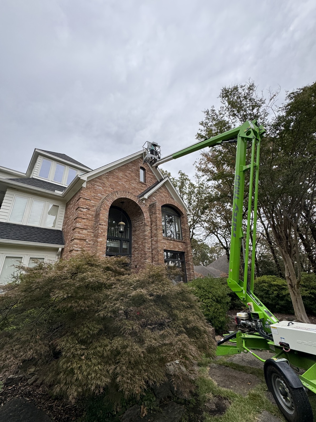 Pug Lights crew using a lift to install lighting on a tall brick home