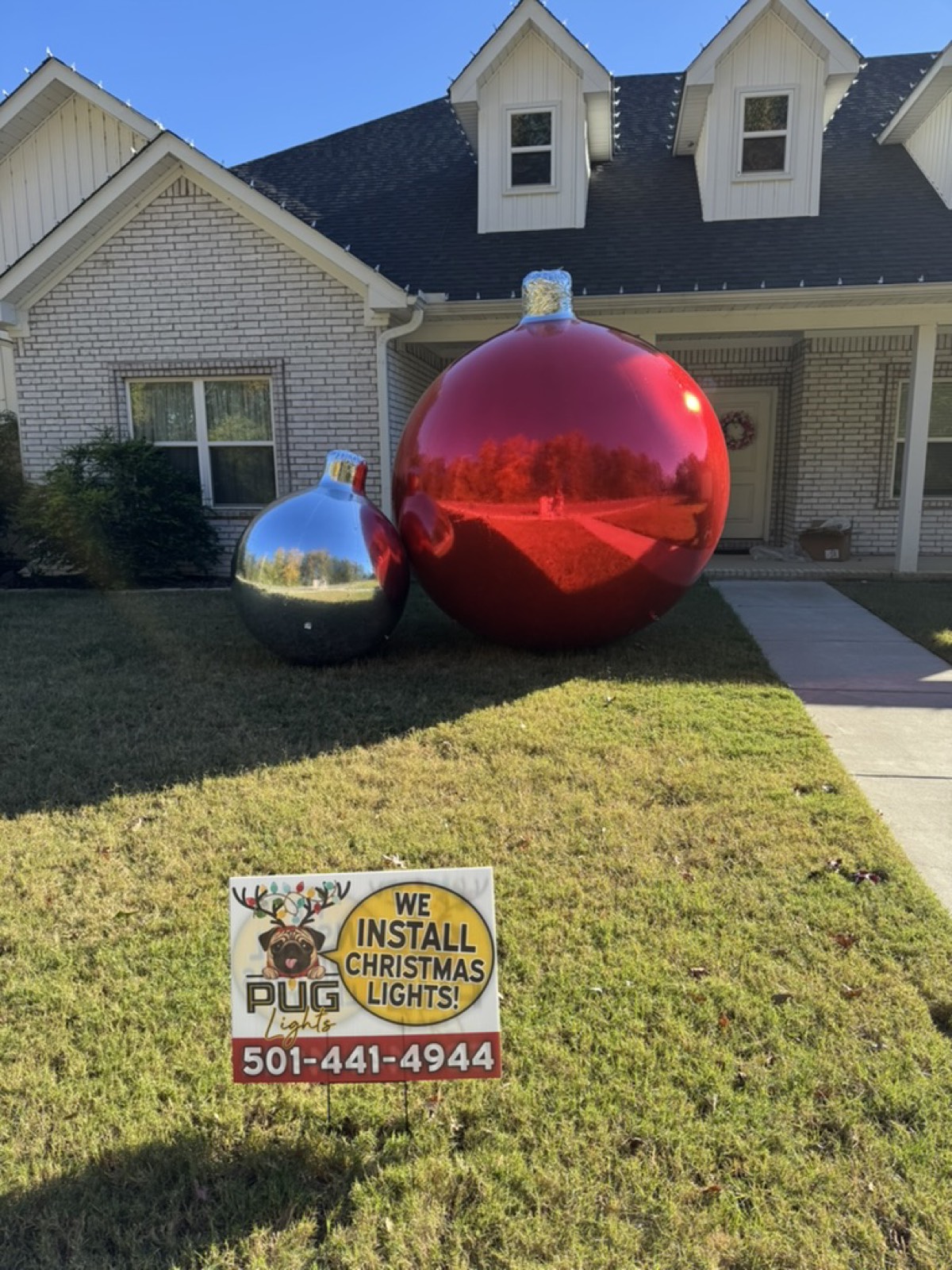 Giant ornament yard decor with a Pug Lights yard sign in front of a home