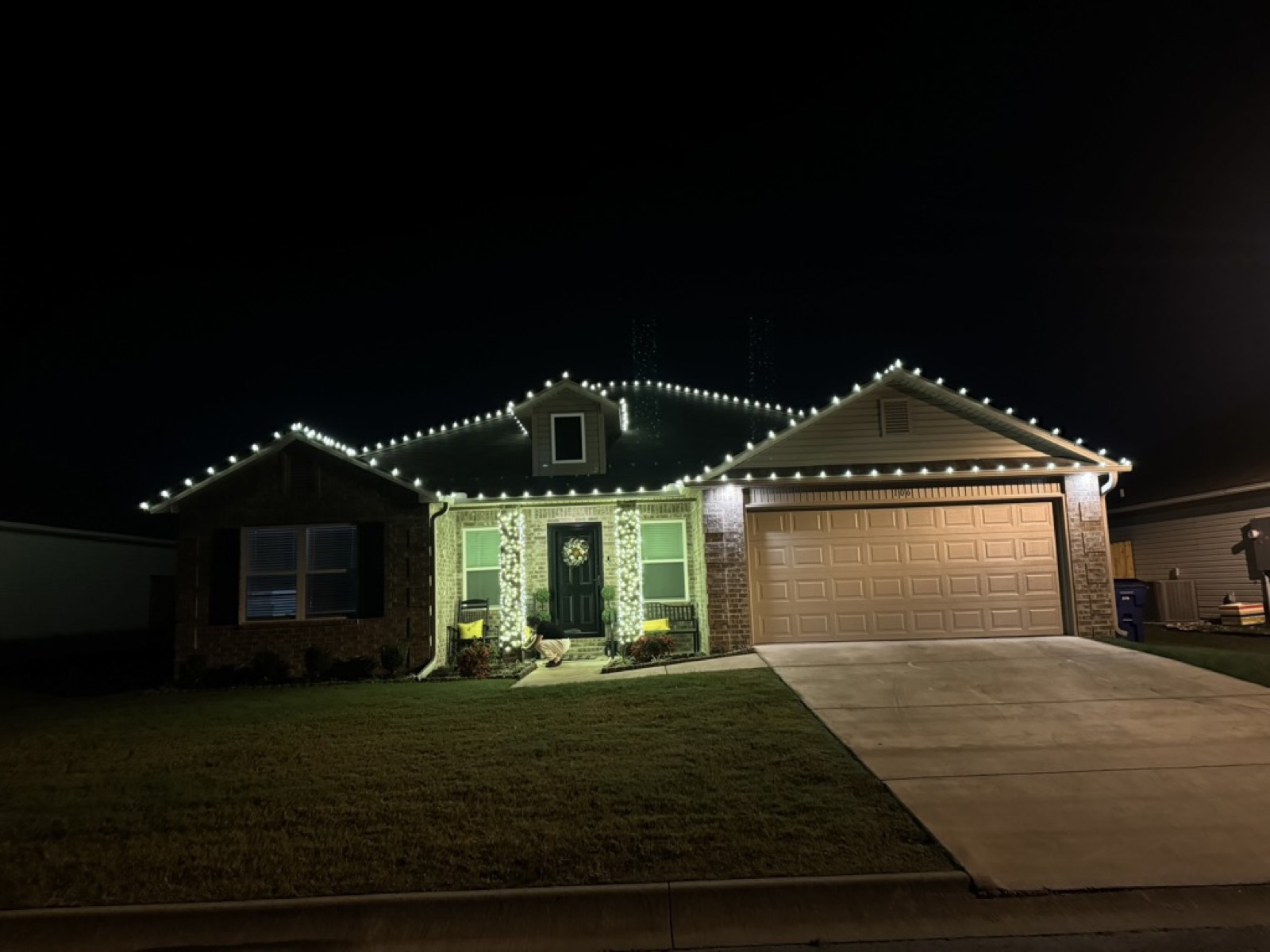 Home with a lit wreath and column wrap lighting